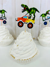 Load image into Gallery viewer, Monster jam inspired monster trucks with a T-Rex dinosaur cupcake toppers. Each monster truck features a T-Rex standing on the back of the truck. The monster truck dinosaur cupcake toppers are professionally printed, cut and attached to four inch bamboo skewers. The monster truck dinosaur cupcake toppers are handcrafted in the USA. The truck options are Grave Digger, Megaladon, El Toro Loco, Tornado and Dragon.
