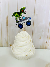 Load image into Gallery viewer, Monster jam inspired monster trucks with a T-Rex dinosaur cupcake toppers. Each monster truck features a T-Rex standing on the back of the truck. The monster truck dinosaur cupcake toppers are professionally printed, cut and attached to four inch bamboo skewers. The monster truck dinosaur cupcake toppers are handcrafted in the USA. The truck options are Grave Digger, Megaladon, El Toro Loco, Tornado and Dragon.