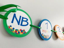 Load image into Gallery viewer, Designed and handcrafted by Declan & Smith Party Decor, this It's a ball to be one first birthday photo banner is the perfect addition to your little one's birthday party! Featuring a ball pit on each month, 13 months, newborn - 12 months and mini clothespin for easily hanging your photos, this banner is fully customizable to perfectly fit your party decor scheme.