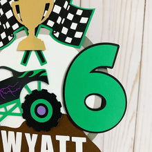 Load image into Gallery viewer, Monster Jam inspired monster truck cake topper. The cake topper features a monster jam inspired monster truck on a dirt mound, a checkered flag, tropy and number. The cake topper is also personalizable with your child's name. The truck options are Grave Digger, Megaladon, El Toro Loco, Tornado and Dragon.