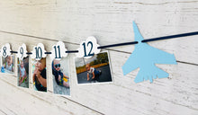 Load image into Gallery viewer, Top Gun fighter jet themed first birthday photo banner. The top gun photo banner features two fighter jets flanking 13 white clouds. The clouds are numbered NB - 12 months for a first birthday. The numbers can be customized to fit any age birthday. The planes, number colors and ribbon color is customizable.