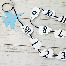 Load image into Gallery viewer, Top Gun fighter jet themed first birthday photo banner. The top gun photo banner features two fighter jets flanking 13 white clouds. The clouds are numbered NB - 12 months for a first birthday. The numbers can be customized to fit any age birthday. The planes, number colors and ribbon color is customizable.