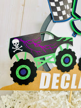 Load image into Gallery viewer, Monster jam inspired dueling monster truck cake topper. The monster jam cake topper features two monster trucks, a checkered flag, dirt mounds, age for the birthday boy or girl and the birthday kiddo's name. The monster jam cake topper is customizable.