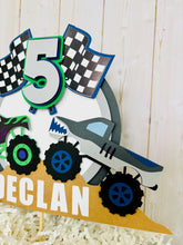 Load image into Gallery viewer, Monster jam inspired dueling monster truck cake topper. The monster jam cake topper features two monster trucks, a checkered flag, dirt mounds, age for the birthday boy or girl and the birthday kiddo's name. The monster jam cake topper is customizable.