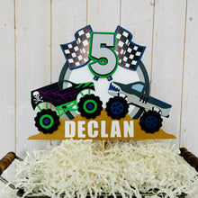 Load image into Gallery viewer, Monster jam inspired dueling monster truck cake topper. The monster jam cake topper features two monster trucks, a checkered flag, dirt mounds, age for the birthday boy or girl and the birthday kiddo's name. The monster jam cake topper is customizable.