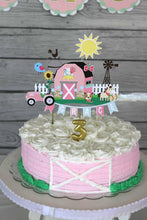 Load image into Gallery viewer, The pink barnyard farm animals cake topper features a pink barn, pink tractor, white picket fence, farm animals and a pink and light blue pennant banner to display your little one's name.