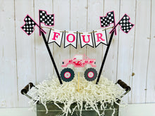 Load image into Gallery viewer, Pink monster truck cake topper. The cake topper is customizable and can display an age, name, word or phrase. The colors are also customizable. The pink monster truck cake topper features two checkered flags, pennant banner and a monster truck to display underneath the bunting. The pink monster truck cake topper is designed and handcrafted by Laura, the owner of Declan & Smith Party Decor.