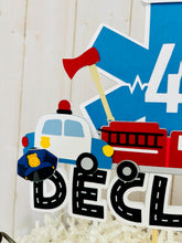 Load image into Gallery viewer, The first responders cake topper features a police car, firetruck, ambulance, road letters, EMT emblem with age and heart beat monitor with a yellow siren.