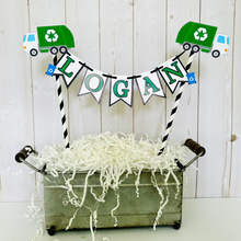 Load image into Gallery viewer, Recycling trash truck cake topper featuring two green trash trucks, pennant with green letters strung between black and white striped paper straws. There are two blue recycling trash bins on the beginning and end letters on the cake bunting cake topper.