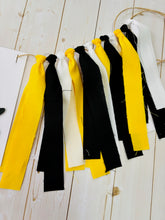 Load image into Gallery viewer, Hockey first birthday high chair banner featuring crossed hockey sticks, hockey puck, layered varsity font letters spelling the word "ONE" and yellow, black and white fabric strips. This hockey first birthday high chair banner is customizable, handcrafted and designed by Laura, the owner of Declan & Smith Party Decor.