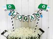 Load image into Gallery viewer, Recycling trash truck cake topper featuring two green trash trucks, pennant with green letters strung between black and white striped paper straws. There are two blue recycling trash bins on the beginning and end letters on the cake bunting cake topper.
