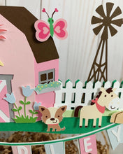 Load image into Gallery viewer, The pink barnyard farm animals cake topper features a pink barn, pink tractor, white picket fence, farm animals and a pink and light blue pennant banner to display your little one's name.