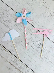 pink airplane centerpiece with a pink airplane, pink and blue pinwheel and white cloud with a blue number one