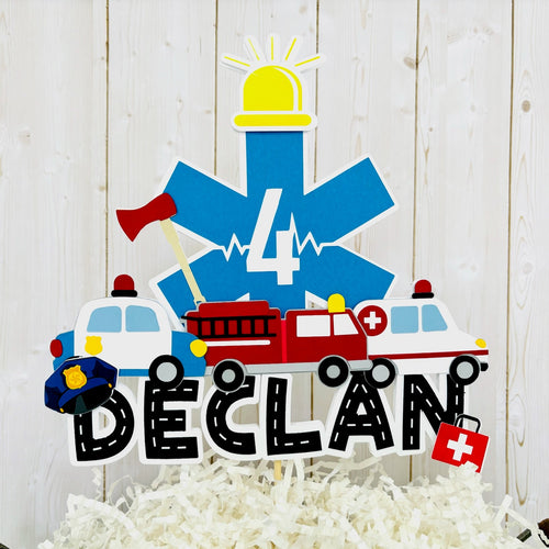 The first responders cake topper features a police car, firetruck, ambulance, road letters, EMT emblem with age and heart beat monitor with a yellow siren. 