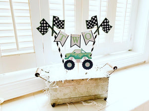 Pink monster truck cake topper. The cake topper is customizable and can display an age, name, word or phrase. The colors are also customizable. The pink monster truck cake topper features two checkered flags, pennant banner and a monster truck to display underneath the bunting. The pink monster truck cake topper is designed and handcrafted by Laura, the owner of Declan & Smith Party Decor. 