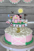 Load image into Gallery viewer, The pink barnyard farm animals cake topper features a pink barn, pink tractor, white picket fence, farm animals and a pink and light blue pennant banner to display your little one&#39;s name. 
