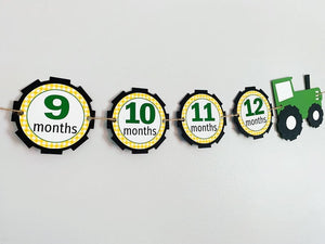 Red tractor photo banner for a first birthday tractor themed birthday party. The red tractor photo banner is available in multiple colors and numerous options for the months. A closed cab flanks each end of the banner and thirteen months are attached to tractor tires where you will hang your photos.