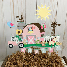 Load image into Gallery viewer, The pink barnyard farm animals cake topper features a pink barn, pink tractor, white picket fence, farm animals and a pink and light blue pennant banner to display your little one&#39;s name. 
